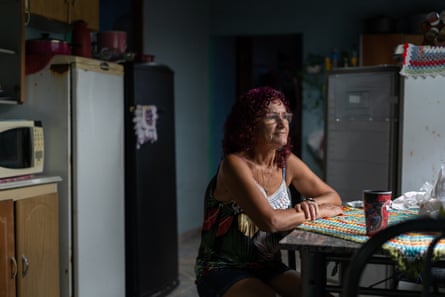 Uma mulher branca mais velha está sentada à mesa da cozinha