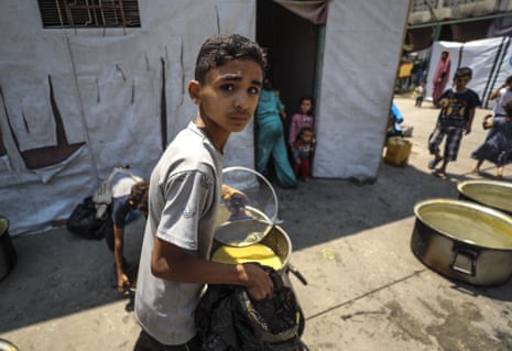 A Palestinian boy carries a hot meal distributed by a charity in Gaza City.