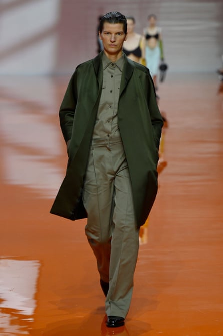 A model wearing a military-style outfit walks the catwalk.