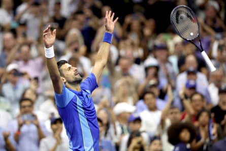 Novak Djokovic throws his racquet in the air and arms up as he celebrates his win