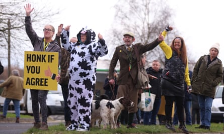 Farmers on a roadside in Preston with a sheep and one dressed as a cow with a sign ‘Honk if you agree’
