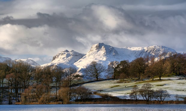 The snow capped Langdale Pikes in the Lake District National park, viewed across Loughrigg Tarn