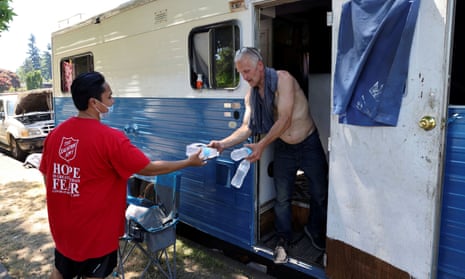 The Salvation Army’s Shanton Alcaraz gives bottled water to resident Eddy Norby, and invites him to a nearby cooling center during a heat wave in Seattle, Washington, on 27 June 2021.
