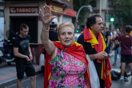 a woman in a pink dress and a red cape takes part in a protest