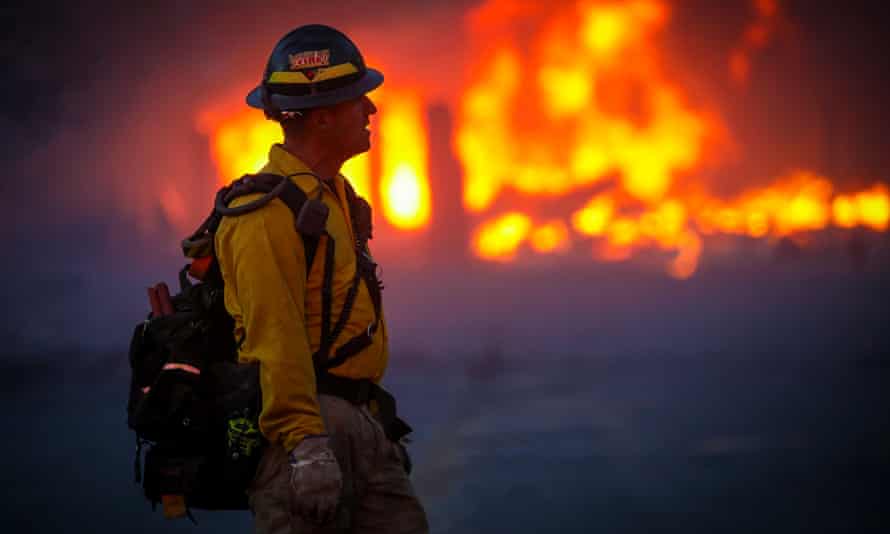 A firefighter walks through the smoke and haze after a fast-moving wildfire swept through Centennial Heights neighborhood of Louisville, Colorado