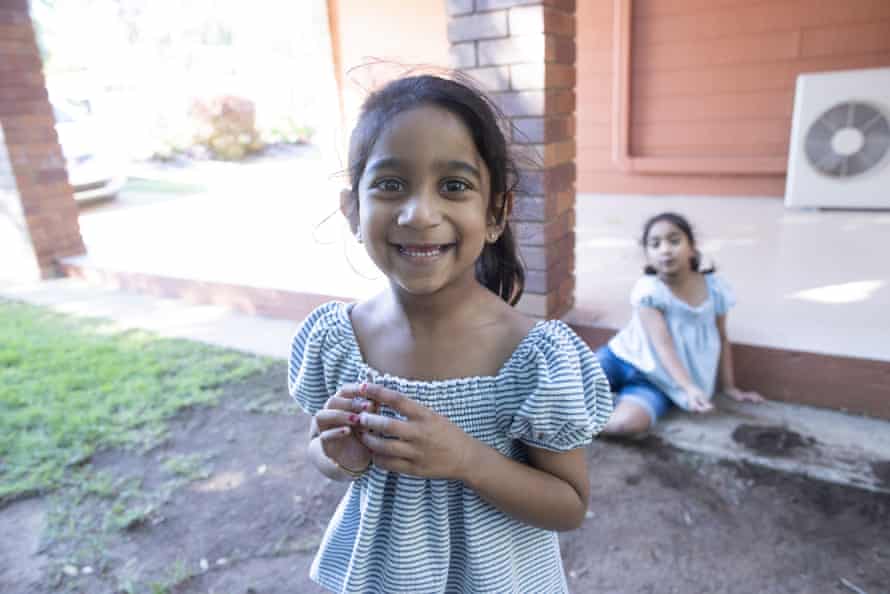 Tharnicaa (front) and Kopika play in the yard of their new home in Biloela.
