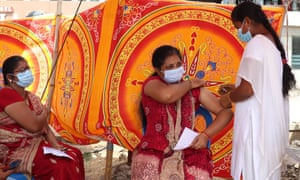 A health worker inoculates a woman with a dose of coronavirus vaccine at a temporary vaccination camp set up in Chennai.