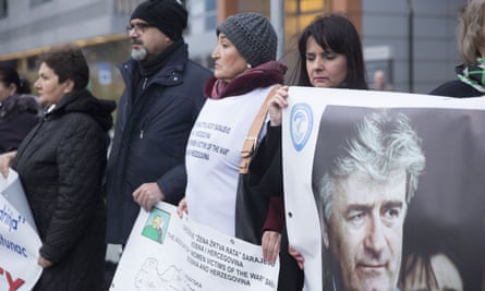 Protesters stand outside court on Wednesday holding posters including one of Radovan Karadzic, a Bosnian Serb former politician and convicted war criminal, as they wait for the verdict against Ratko Mladic