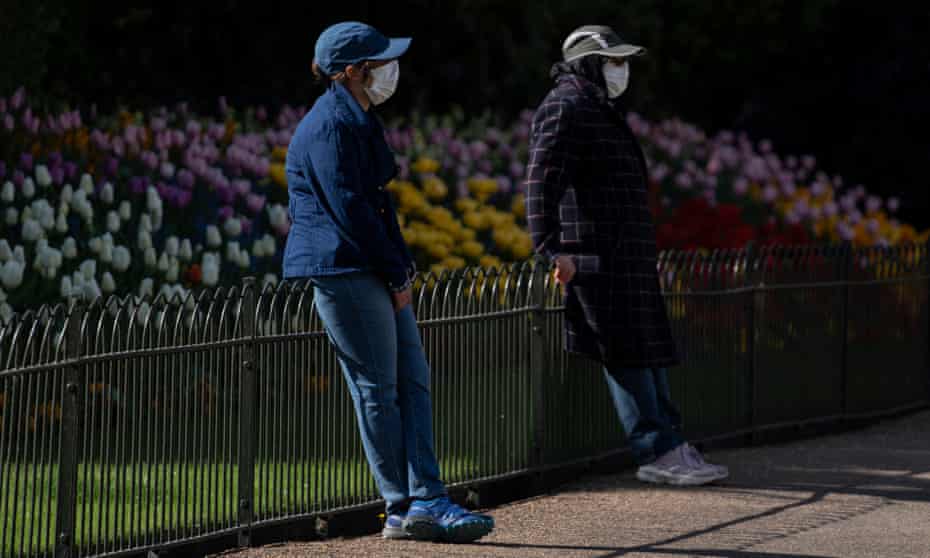 Two people wearing faces mask in St James Park, London