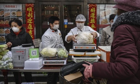 Chinese vendors wear protective masks as they sell vegetables in the street during the Chinese New Year holiday