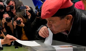 A man wearing a barretina, the traditional Catalan hat, kisses his ballot while voting in Barcelona.