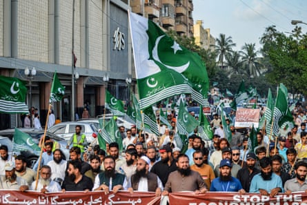 Sakallı erkekler Pakistan tarzında yürüyor ve pankartlar ve yeşil bayraklar sallıyor