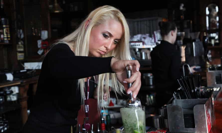 A bar lady makes a mojito cocktail in an English pub