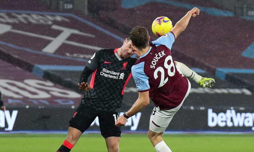 Jordan Henderson of Liverpool (left) clears the ball with his head while Tomas Soucek raises a foot to try and send it goalwards.