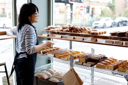 A woman in jeans and a striped cotton top chooses a cake from a window display