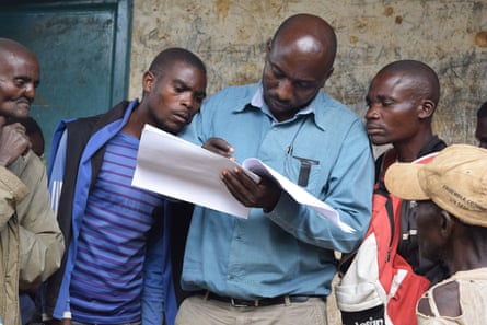 A man stands checking off a list while men look on