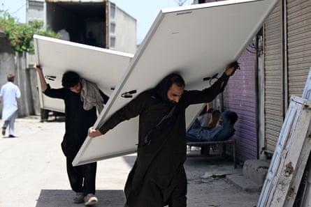 Workers unload solar panels from a truck