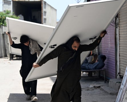 Workers unload solar panels from a lorry