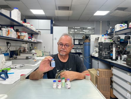 An older man holds vials in a laboratory