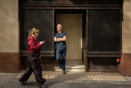 Gleeson stands in a doorway as a woman walks past