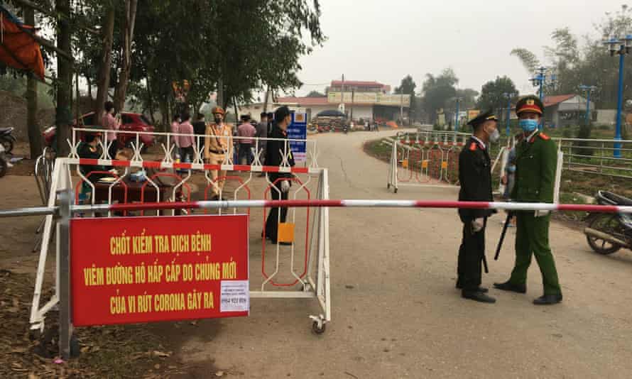 Police wearing masks guard a road checkpoint outside Son Loi in Vietnam