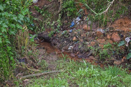 View of a river and riverbank near a tea planation in Sri Lanka that is strewn with rubbish.