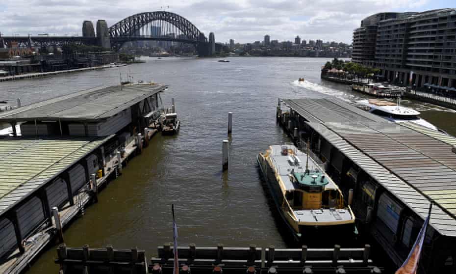Sydney Harbour ferry terminal with murky brown water and the Sydney Harbour Bridge in the background.