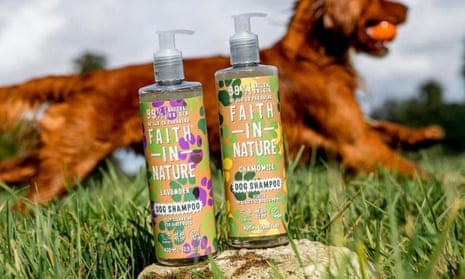 Bottles of Faith In Nature dog shampoo in front of a dog reclining on grass