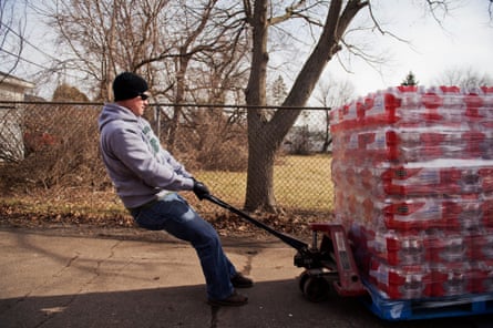 A delivery man hauls bottled water outside of the St Mark Baptist church in Flint, Michigan, on 23 February 2016.