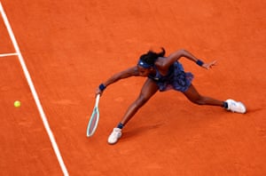 Coco Gauff slides towards a backhand ball on a clay court