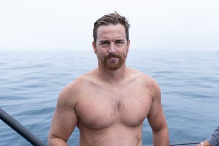 Swimmer Jono Ridler on a boat with the sea behind him