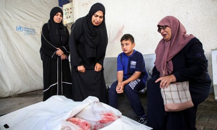 Three adults and a child attend the funeral for Palestinians killed in an Israeli strike in Rafah.