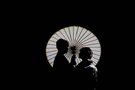 A couple pose in black silhouette with a parasol