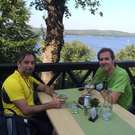 Two men sitting at a table holding drinks.
