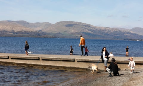 People walking on a stone jetty on the loch's shore