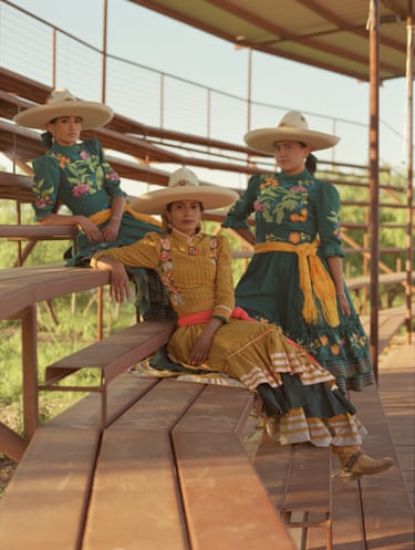 Three women in traditional dress pose on a spectator stand