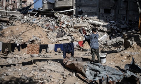 A person hangs washing on a line amid rubble