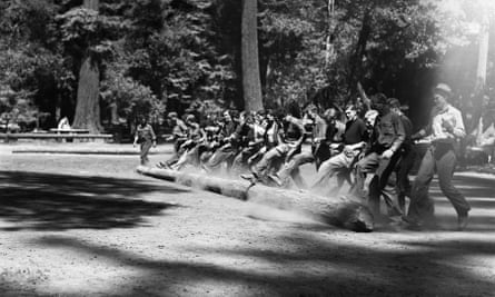 A group of teenage boys roll a log across a clearing at the CCC camp in Redwood state park.
