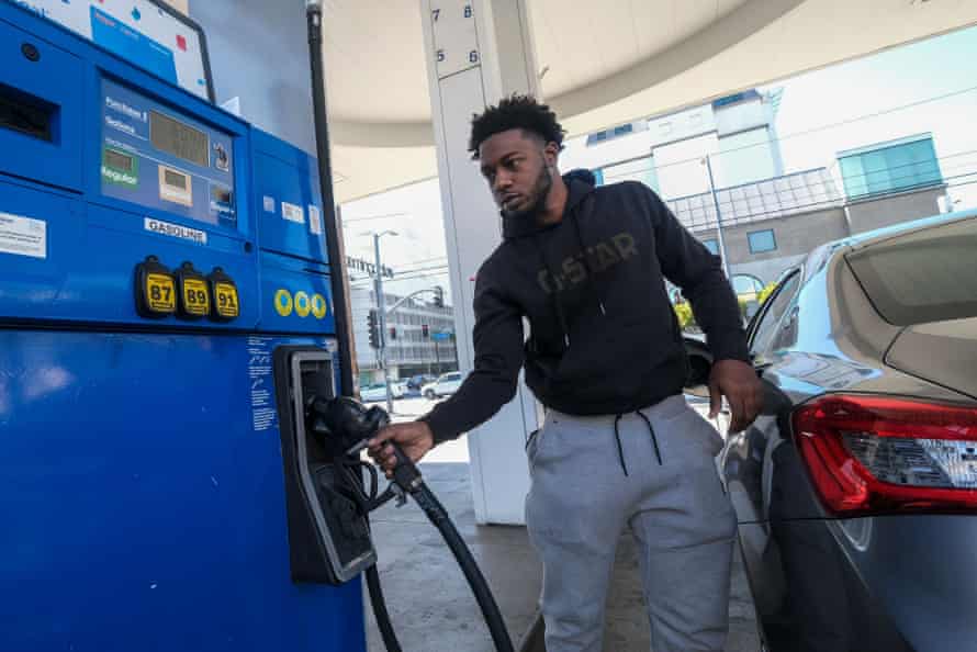 A man grabs the handle of a gas pump as he prepares to fill his car’s gas tank. The digital readout on the gas pump shows $6.19 for a gallon of regular gas.