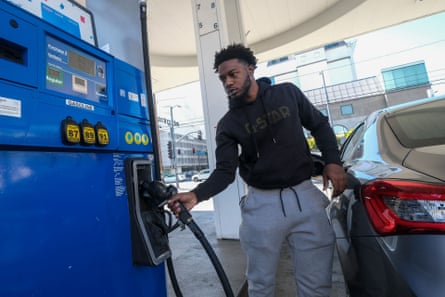 A man grabs the handle of a gas pump as he prepares to fill his car’s gas tank. The digital readout on the gas pump shows $6.19 for a gallon of regular gas.