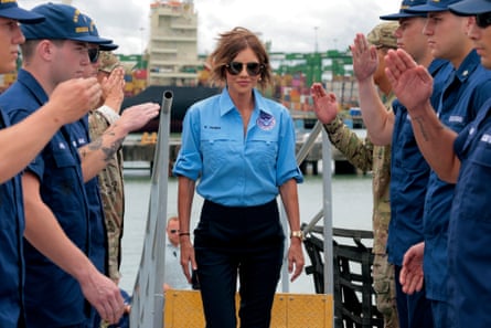 Woman in aviator sunglasses boarding ship as those around her salute