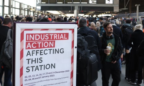 Travellers at St Pancras International station surrounding a poster signalling industrial action