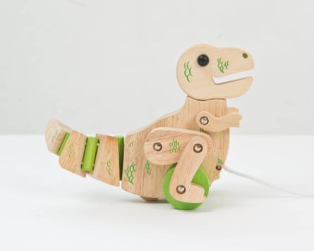 A wooden toy dinosaur. The dinosaur has a bendy tail, metal screw joints and green highlights.