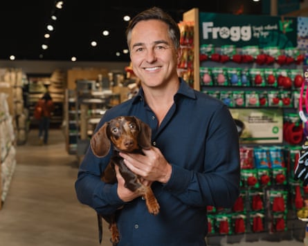 Man holds small dog in aisle of shop