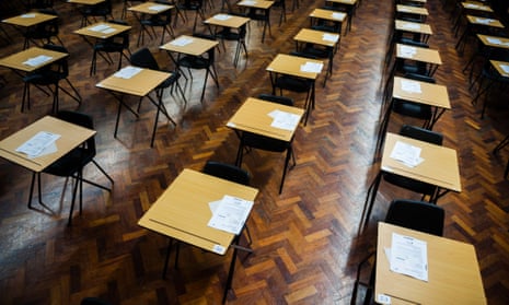 Rows of empty desks ready for pupils to sit their exams in a school hall.