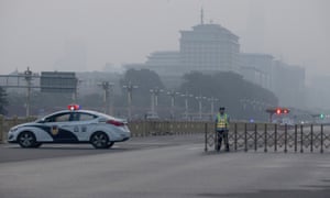 A traffic warden and police vehicle block the road leading to Tiananmen Square.