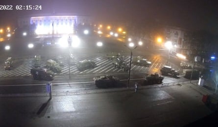 Army vehicles in a brightly lit square at night