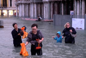 People walk in a flooded Saint Mark Square during a period of seasonal high water in Venice, Italy