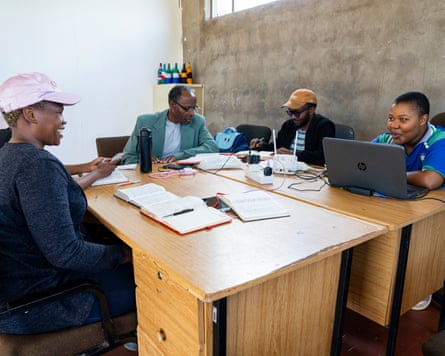 Four people working around a pair of desks, smiling