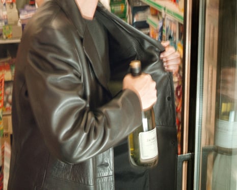 Shoplifting (posed by a model). The person is about to hide a bottle under their coat